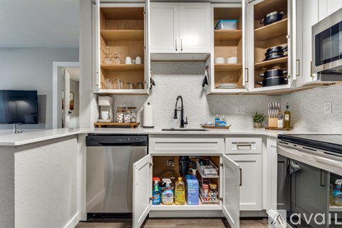 A kitchen with white cabinets and appliances, and a white tiled backsplash.
