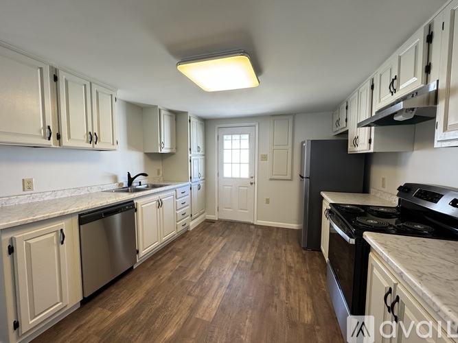 A kitchen with white cabinets and a wooden floor.