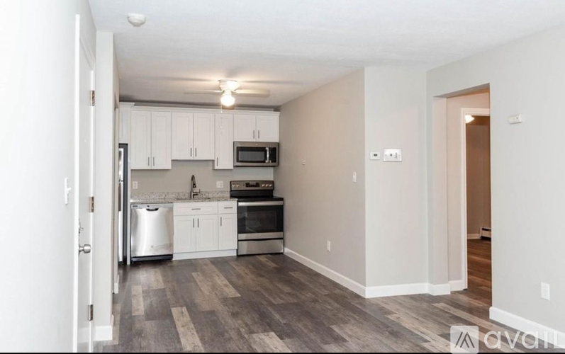 A kitchen with white cabinets and a grey floor.