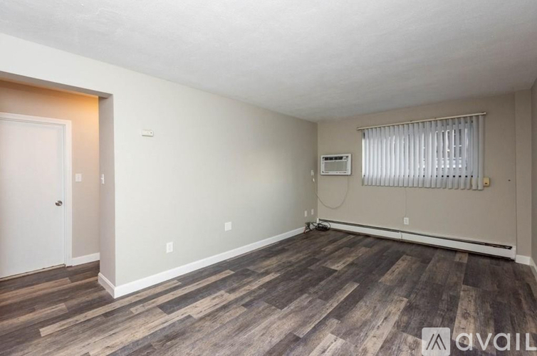 A room with wooden flooring and a window with blinds.