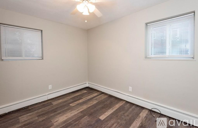 A room with wooden flooring and two windows.