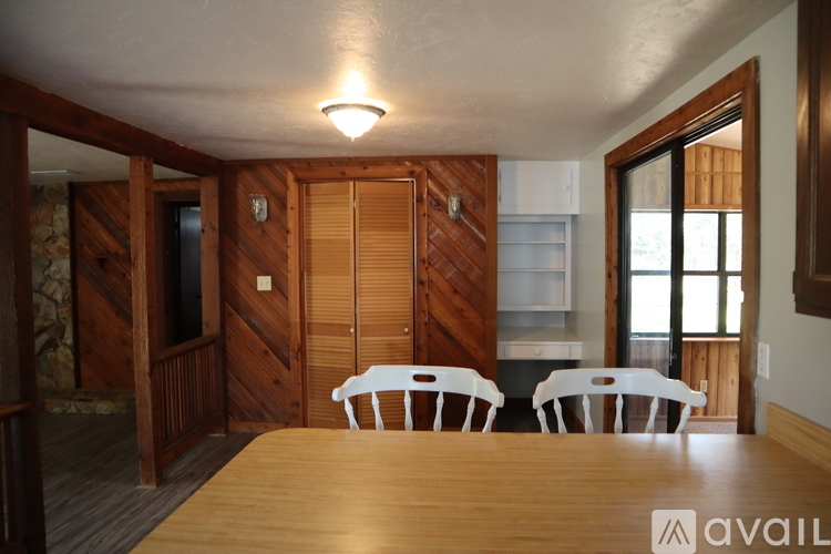 A wooden table with four chairs in a room with a wooden door.