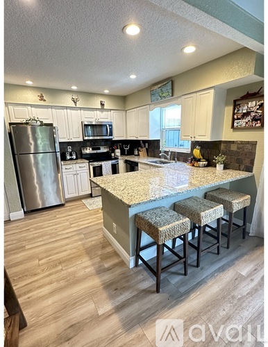 A kitchen with a refrigerator, microwave, and stove top oven.
