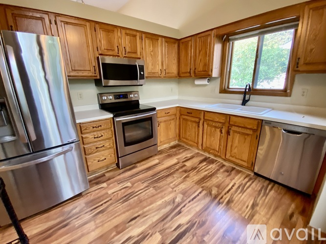 A kitchen with wooden cabinets and a stainless steel refrigerator.