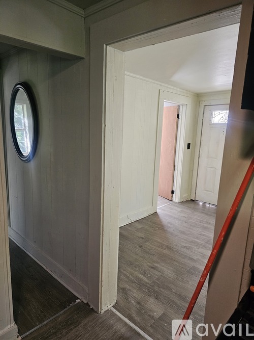 A hallway with a white door and a round mirror on the wall.
