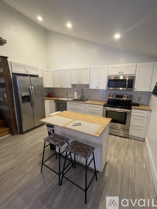 A kitchen with white cabinets and a wooden island.