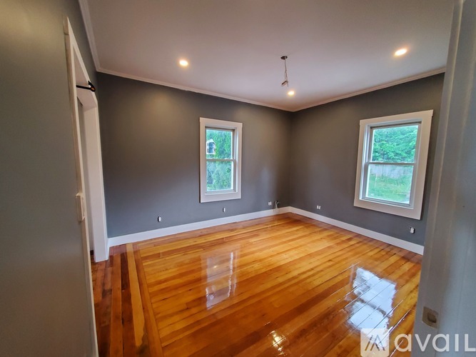 A room with wooden floors and two windows.