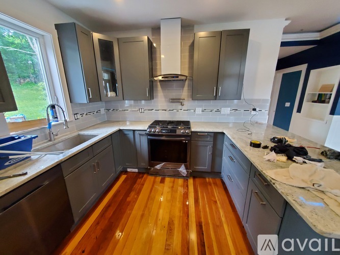 A kitchen with wooden floors and a stove top oven.