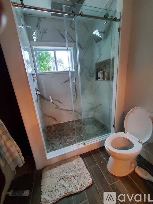 A toilet in a bathroom with a glass shower door.