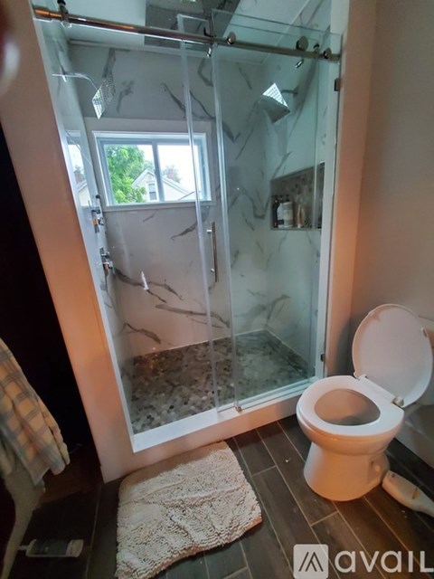 A toilet in a bathroom with a glass shower door.