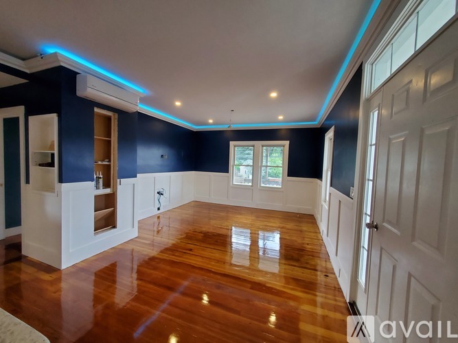A spacious room with wooden floors and white walls.
