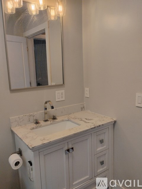 A bathroom with a marble countertop and a mirror above the sink.