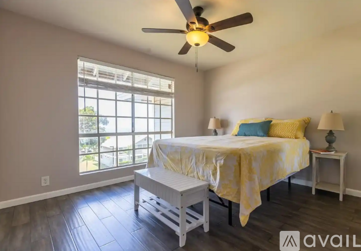 A bedroom with a bed, a bench, and a ceiling fan.