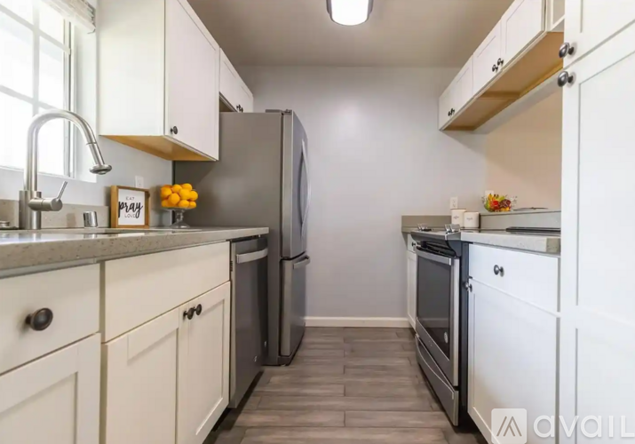 A kitchen with white cabinets and a black refrigerator.