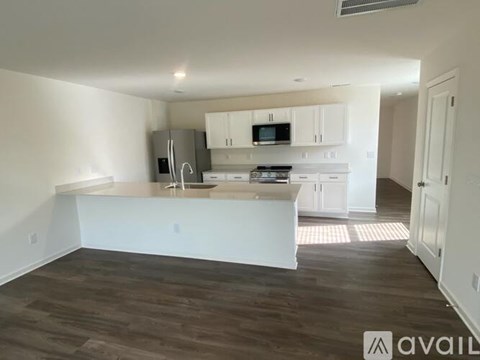 A kitchen with white cabinets and a wooden floor.