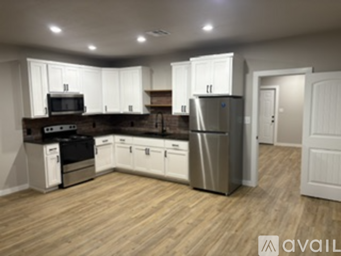 A kitchen with white cabinets and a wooden floor.