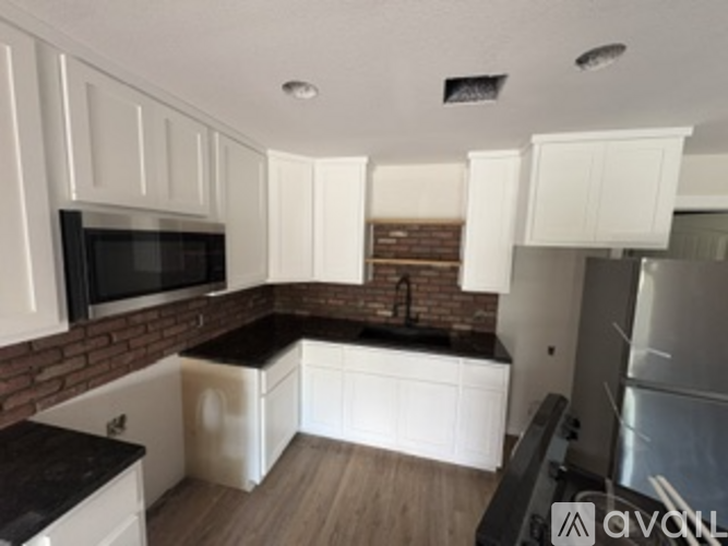 A kitchen with white cabinets and a brick wall.