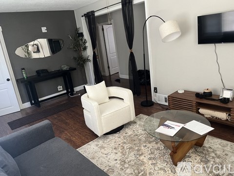 A living room with a white chair and a grey rug.