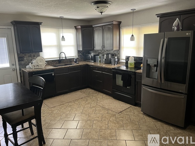 A kitchen with a tile floor and dark wood cabinets.