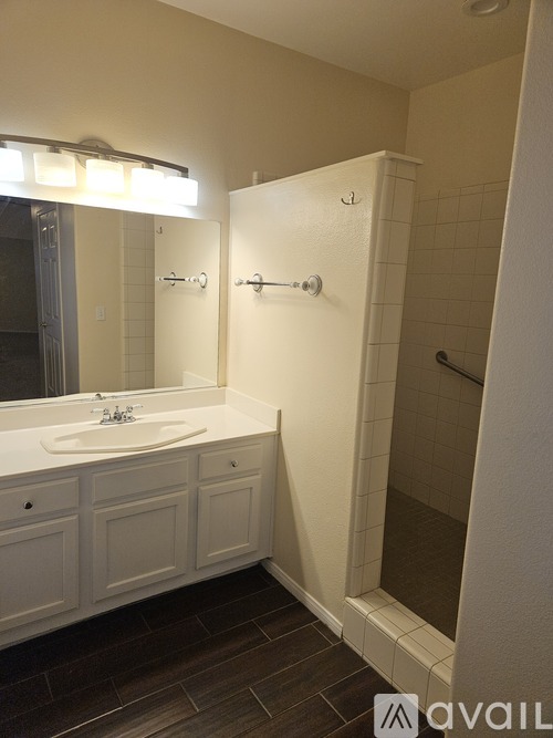 A bathroom with a sink, mirror, and shower.