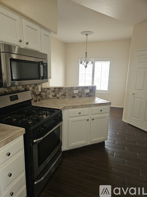 A kitchen with black appliances and white cabinets.