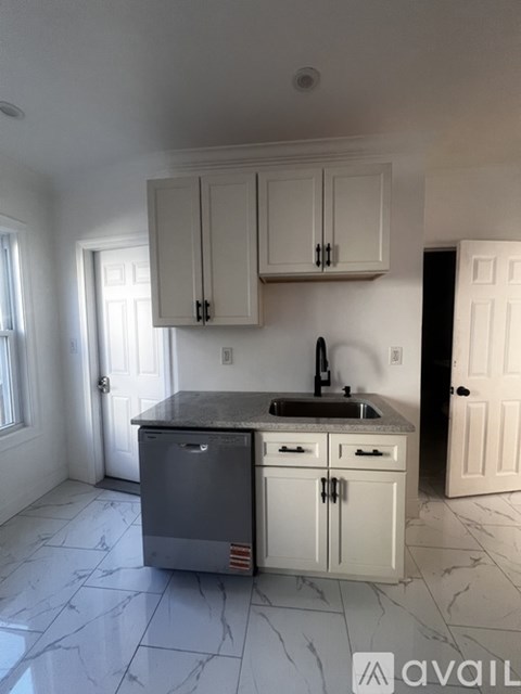 A kitchen with white cabinets and a marble countertop.