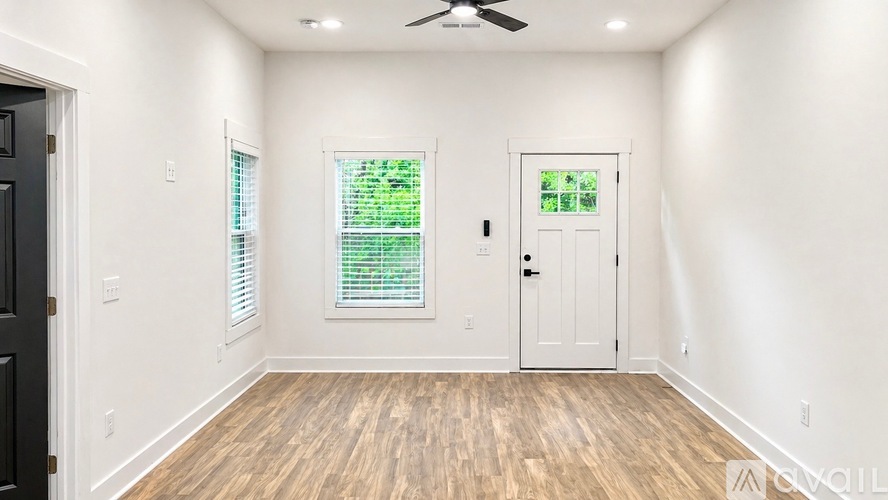 A room with a black door, a window with blinds, and a ceiling fan.