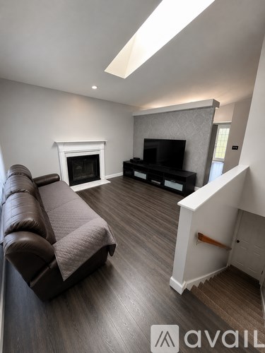A living room with a brown leather couch and a fireplace.