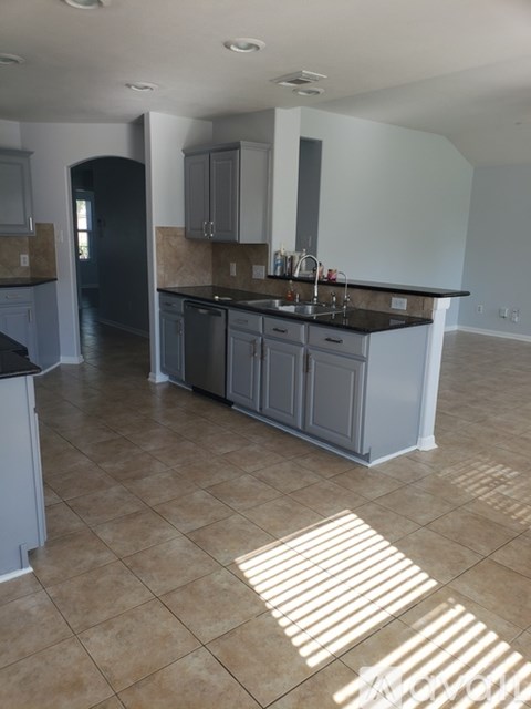 A kitchen with a black refrigerator and a sink.