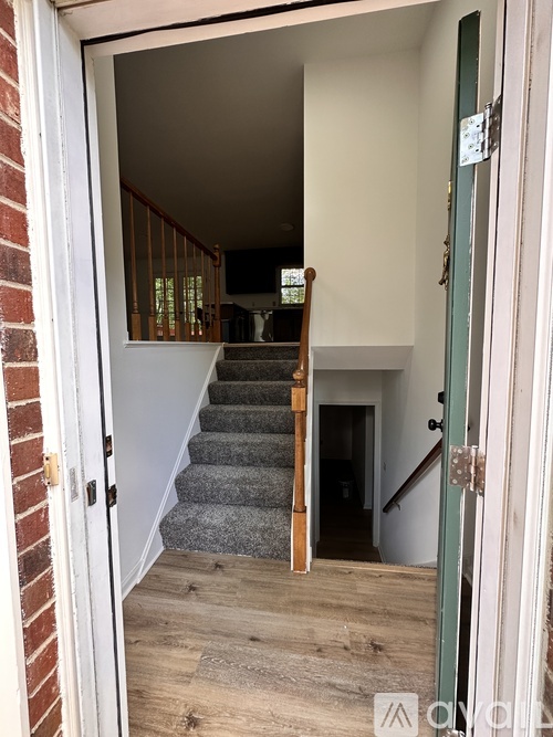 A white door is open to a hallway with a staircase.