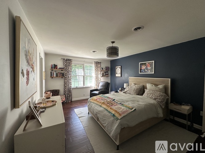 A bedroom with a large bed and a painting on the wall.