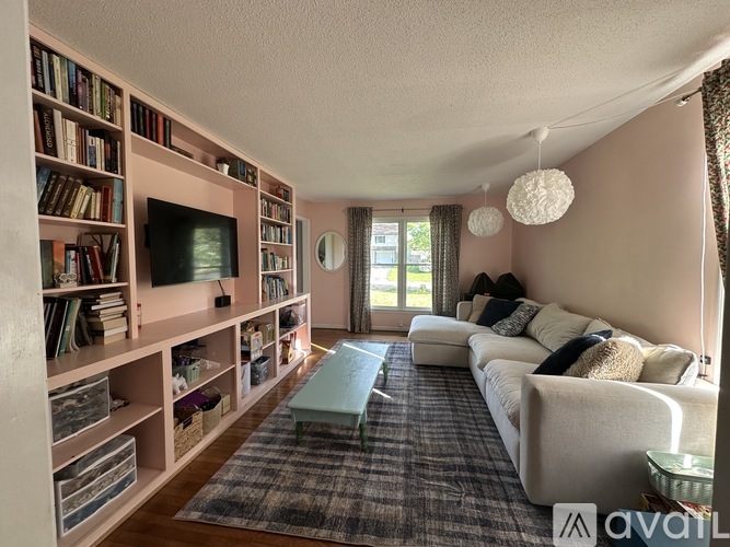 A living room with a white couch, a television, and a bookshelf filled with books.
