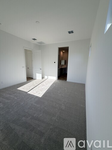 A room with a carpeted floor and a door on the left side.