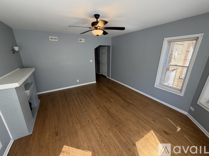 A room with a ceiling fan and wooden flooring.