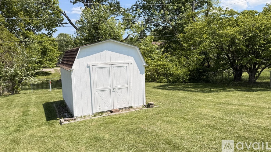 A small white shed sits in a grassy field.
