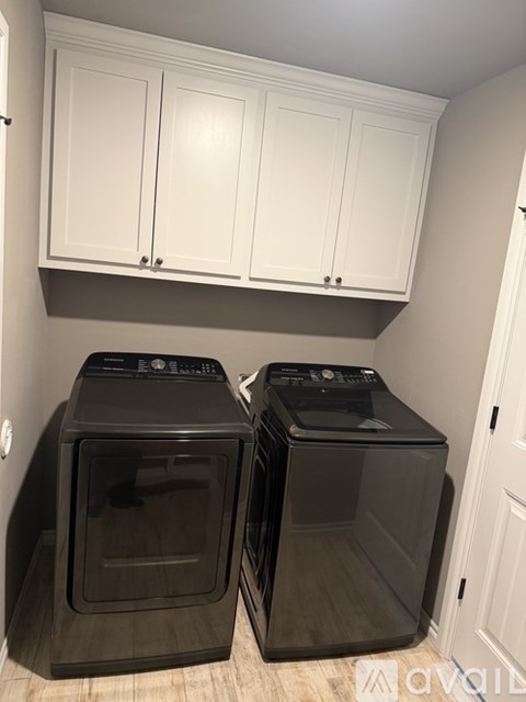 Two black ovens are in a kitchen under white cabinets.