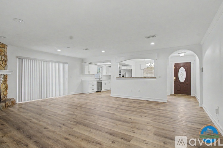 A spacious room with wooden flooring and white walls.