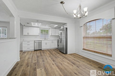 A kitchen with white cabinets and a wooden floor.