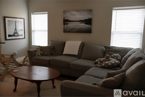 A living room with a grey couch, a wooden coffee table, and a painting on the wall.
