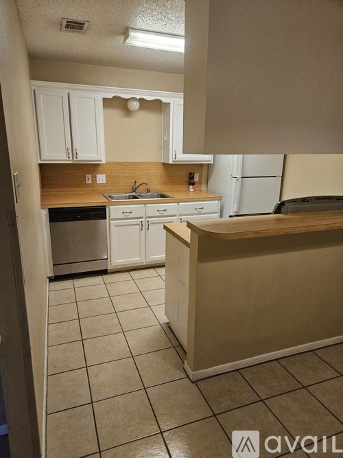 A kitchen with white cabinets and a wooden counter.