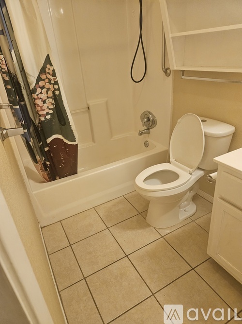 A bathroom with a toilet, a tub, and a towel hanging on the shower rod.