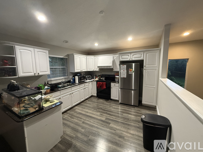 A kitchen with white cabinets and a black trash can.