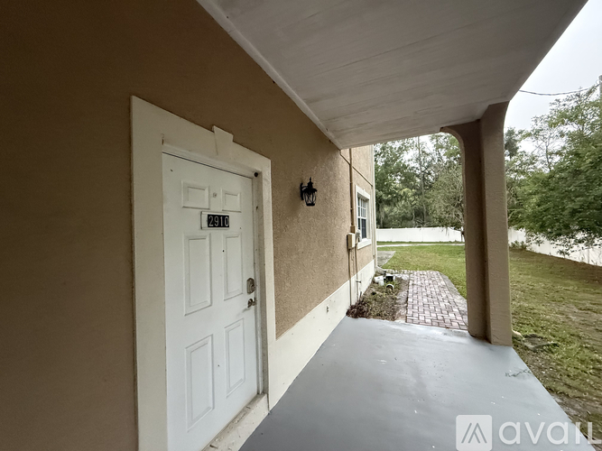 A white door with a black handle is on the left side of a covered walkway.