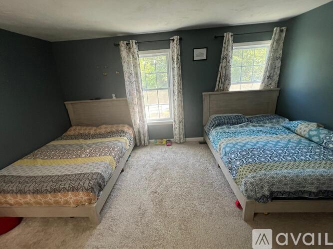 A bedroom with two beds and carpeted floor.