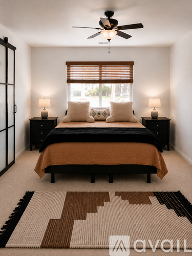 A bedroom with a bed, two lamps, and a rug.