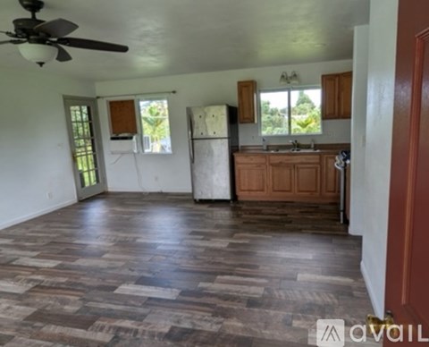 A kitchen with wooden floors and a ceiling fan.