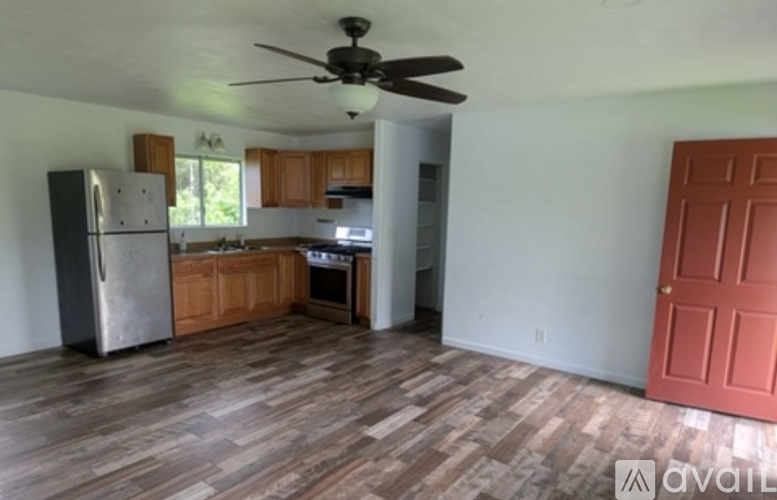 A kitchen with a refrigerator, wooden cabinets, and a ceiling fan.