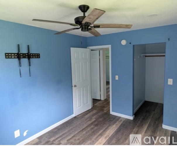 A room with a ceiling fan and a wooden floor.