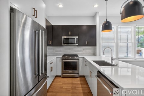 A modern kitchen with a stainless steel refrigerator and wooden floors.