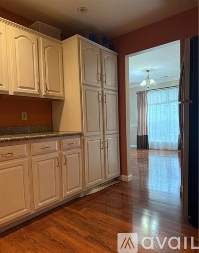 A kitchen with white cabinets and a wooden floor.